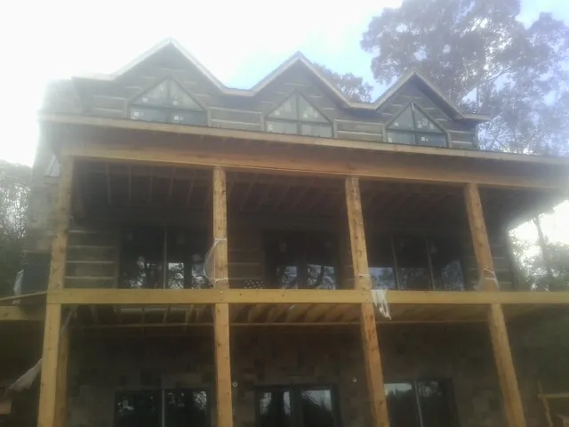 Dormers and porch framing on a large log home under construction — Roof Coating work by our crew in Kittredge