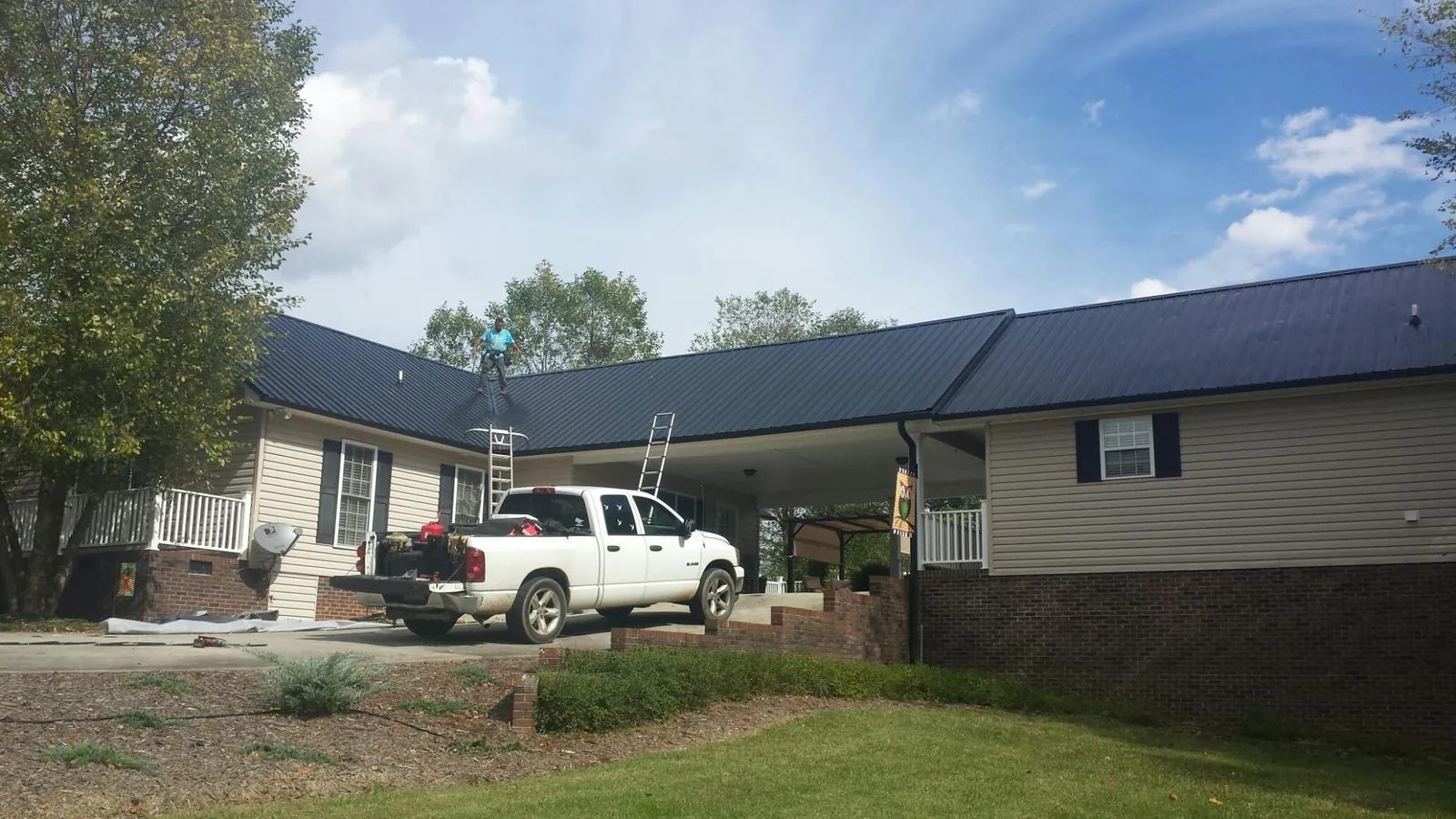 Black metal roof over a home and attached breezeway with ladders set in Kittredge