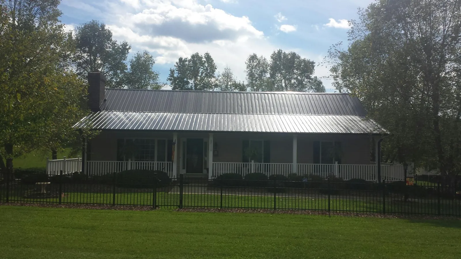Gray metal roof on a brick ranch with a full width front porch — Gutter Guard Installation work by our crew in Kittredge